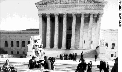 Image: At the base of the Supreme Court, Not Dead Yet holds its sign; 

farther up, groups supporting assisted suicide gather.