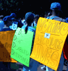 marchers with signs on back reading 